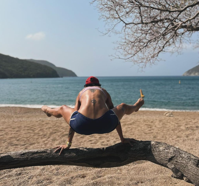 Caro doing a yoga pose on a fallen tree branch at a beach in colombia. Chandra Vida retreats.