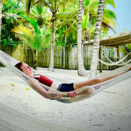 Diana swings gentrly in the breeeze in a hammock by the beach before yoga practice. Chandra Vida Retreats.