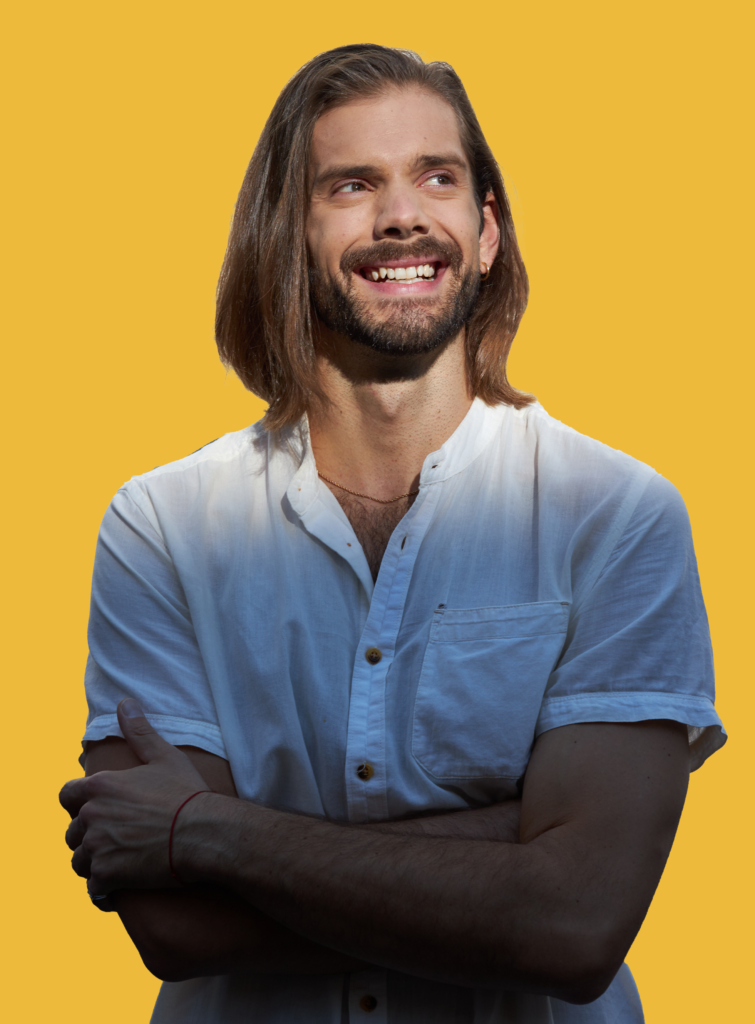 Levi profile picture with yellow background. He is standing with his arms crossed with a big smile.At a Chandra Vida yoga retreat.