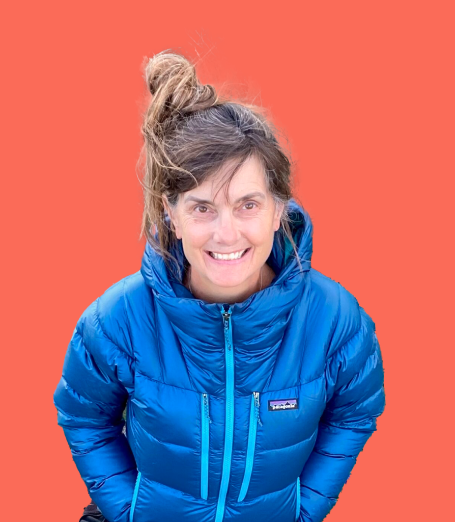 Stacey profile picture. She is wearing an electric blue puffy coat with an orange background. Chandra Vida retreats.