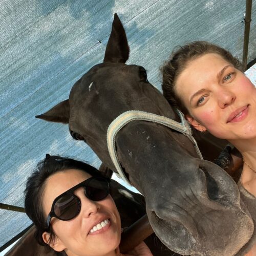 Carolin and Mariana pose for a picture with a brown polo pony. Chandra Vida Retreats.